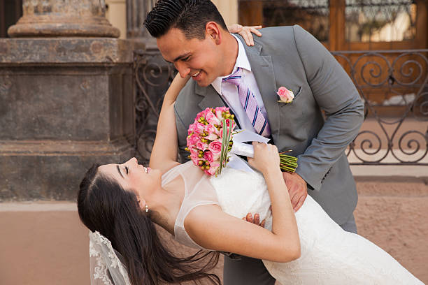 Handsome groom and his bride leaning down for a kiss outside a church