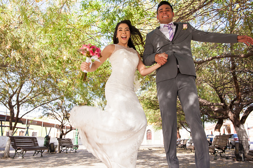 Excited bridal couple jumping and celebrating on their wedding day outdoors