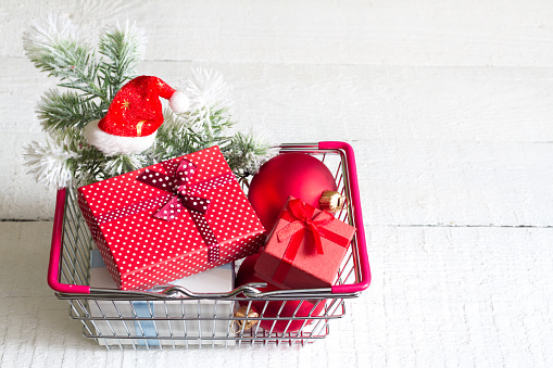 Gifts in shopping basket on a white christmas symbol