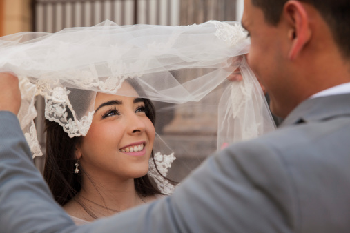 Point of view of a groom lifting her bride's veil and uncovering her face