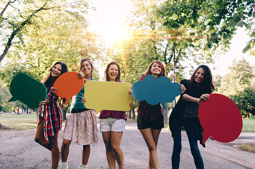 Group of teenage girls holding blank speech bubbles and looking at camera