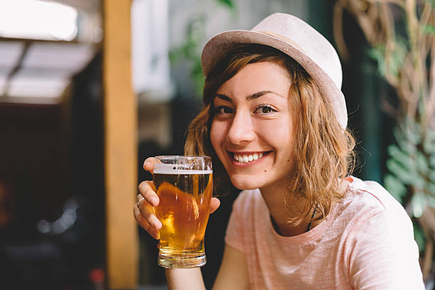 lächelnde frau hält einen schoppen bier - festival alcohol stock-fotos und bilder