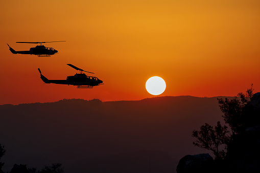 Two flying army helicopters on sunset background