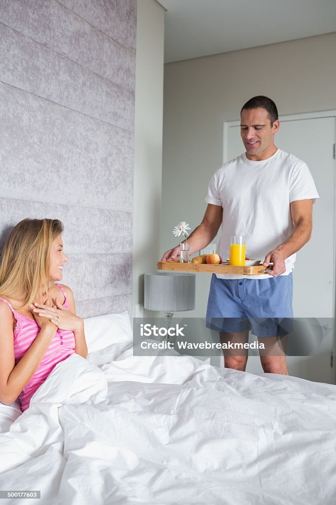 Souriant femme surpris par le partenaire apportant le petit déjeuner au lit - Photo de Adulte libre de droits