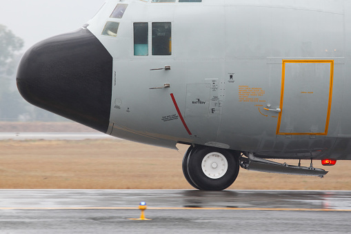 C-130 military transport airplane taxiing on runway under the rain