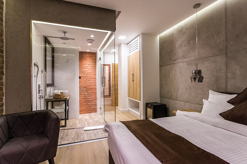 Modern hotel en suite bathroom. Stainless steel washing baisin and glass shower cabin.