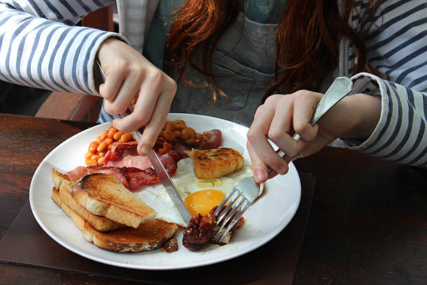 mädchen isst englisches gebratener frühstück, würstchen, eiern, speck, gebackene-bohnen - breakfast eating people teens stock-fotos und bilder