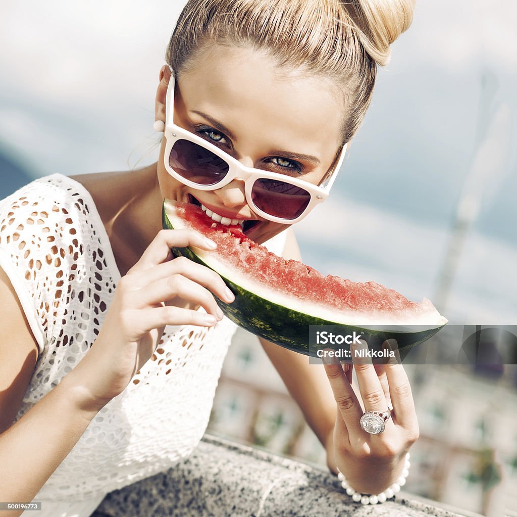 girl in white summer dress eat watermelon beautiful young girl with bow tie hair in white summer dress wearing sunglasses bites juicy watermelon Eating Stock Photo