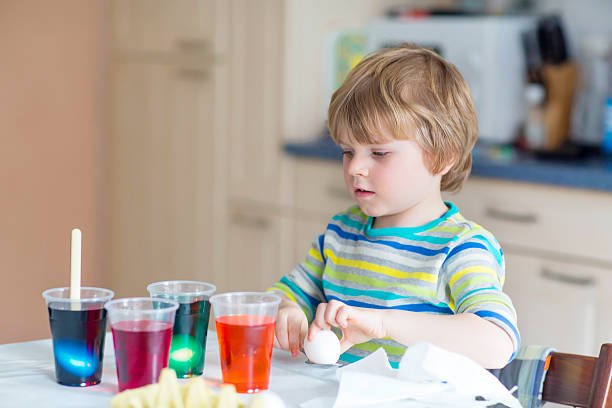 istock Little kid boy coloring eggs for Easter holiday 500198090