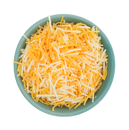 Top view of a small bowl filled with shredded white cheddar, sharp cheddar and mild cheddar cheeses isolated on a white background.