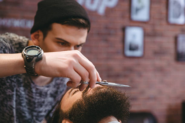 istock Young consentrated barber grooming beard of  man with scissors 500200428