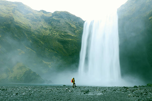 excursionistas al majestuoso catarata de skógafoss en islandia - large waterfall fotografías e imágenes de stock