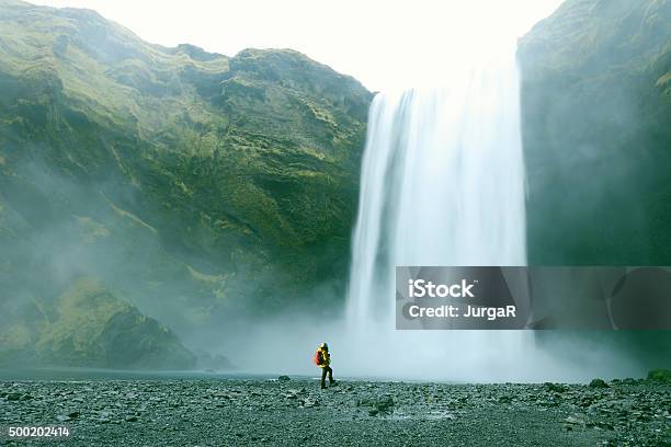 Hiker At Majestic Skogafoss Waterfall In Iceland Stock Photo - Download Image Now - Large, Small, Waterfall
