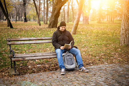 Young men reading a book in the park.
