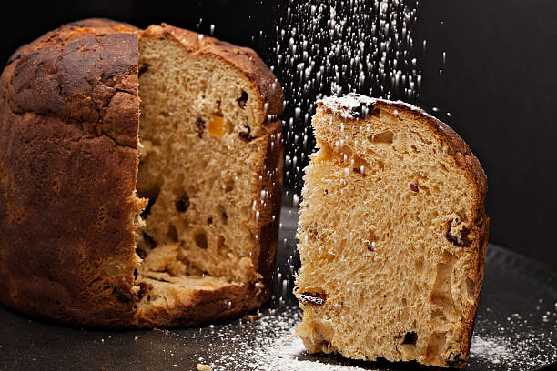 Slice Of Panettone A close up, horizontal photograph of a golden slice of panettone being sprinkled with  powdered sugar. sprinkling powdered sugar stock pictures, royalty-free photos & images