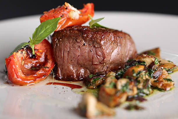 carne assada com tomate e cogumelos em um prato branco - prepared potato vegetable meat food - fotografias e filmes do acervo