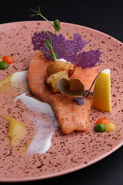 istock Salmon with sauces, croutons and lemon on plate, black background 500213360
