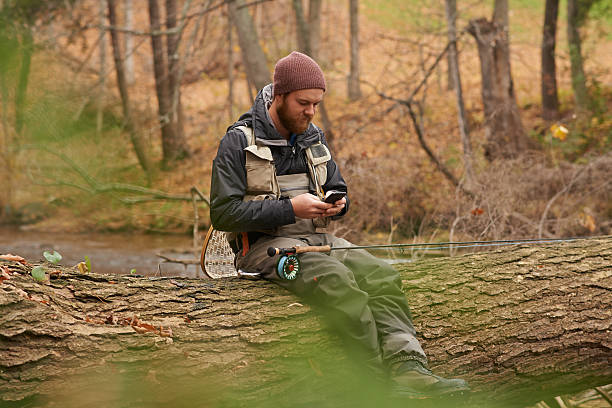 texting one of his mates - forest sitting men comfortable imagens e fotografias de stock