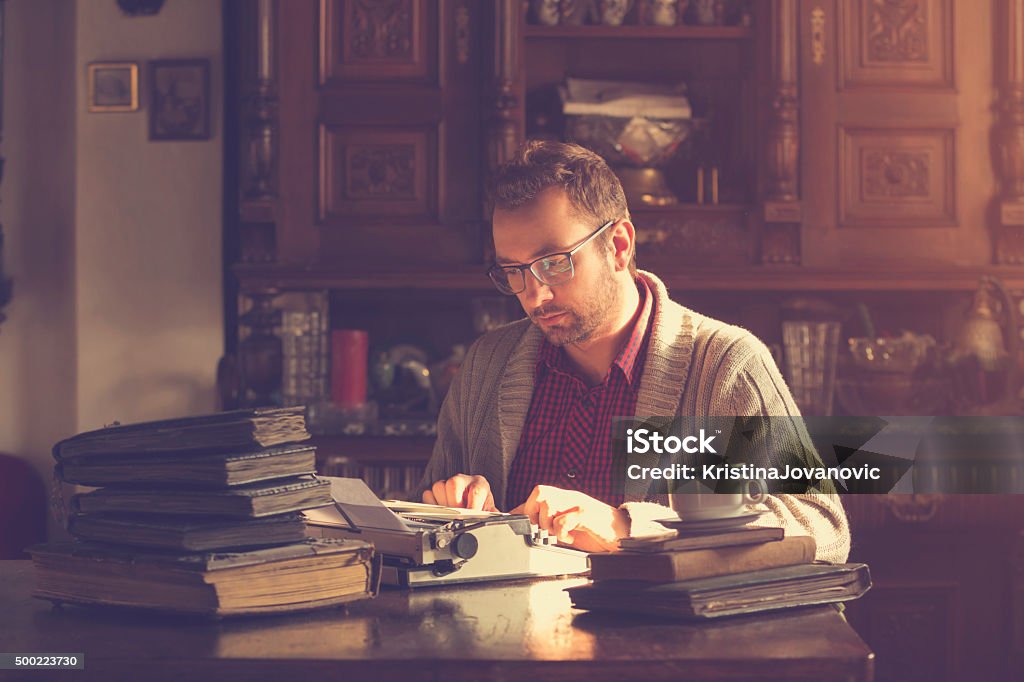 Young man writing on old typewriter. Men Stock Photo