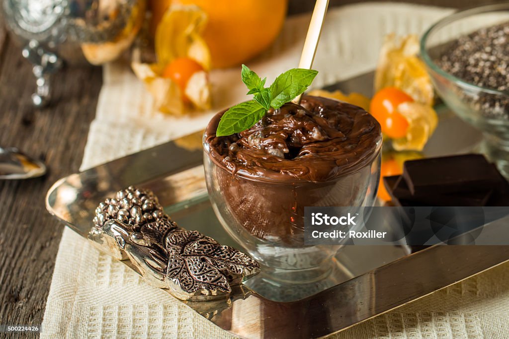 Chocolate chia seed pudding in glass bow Chocolate chia seed pudding in glass bowl with chia seeds, chocolate mandarin and mint  on top on metal tray over wooden background Antioxidant Stock Photo