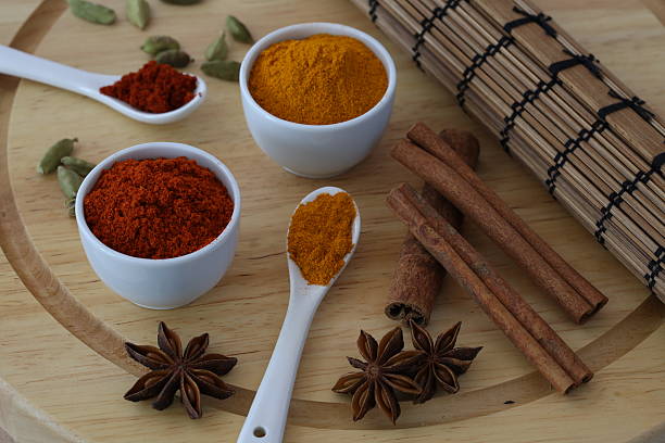 Composition of paprika and turmeric accompanied by star anise, cardamom seeds and cinnamon sticks.