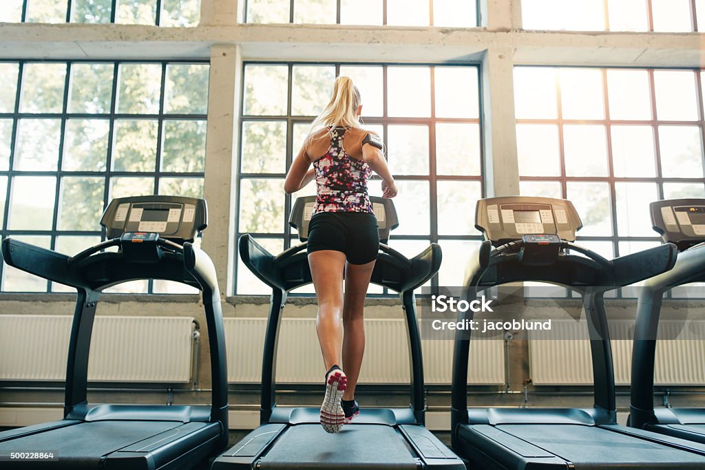 Woman jogging on treadmill Horizontal shot of woman jogging on treadmill at health club. Female working out at a gym running on a treadmill. Treadmill Stock Photo