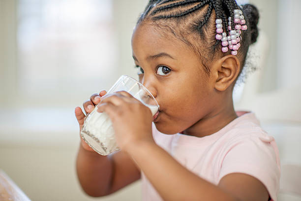 маленькая девочка пить молоко - african descent child little girls african ethnicity стоковые фото и изображения