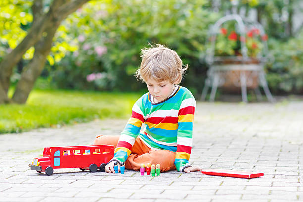 istock Active kid boy playing with red school bus and toys 500231480