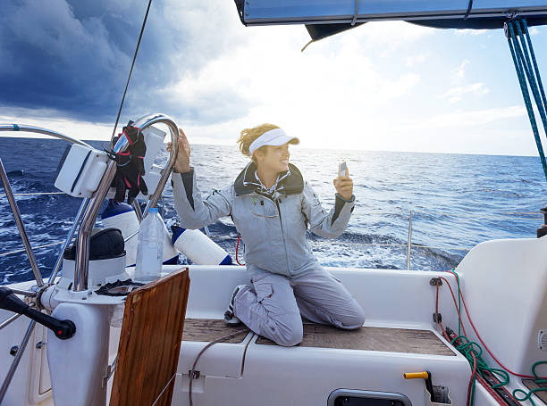 Selfie Woman taking selfie while sailing, moody sky in background, copy space yacht selfie stock pictures, royalty-free photos & images