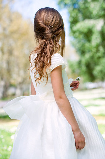 Close up of girl in white dress showing hairstyle outdoors.