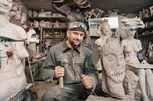 Craftsman creating shape of sculpture in his workshop