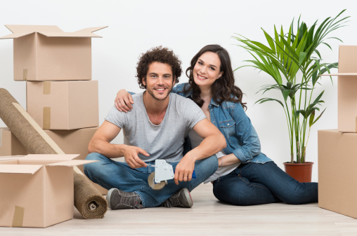 Happy Young Couple Surrounded With Cardboard Boxes At Home