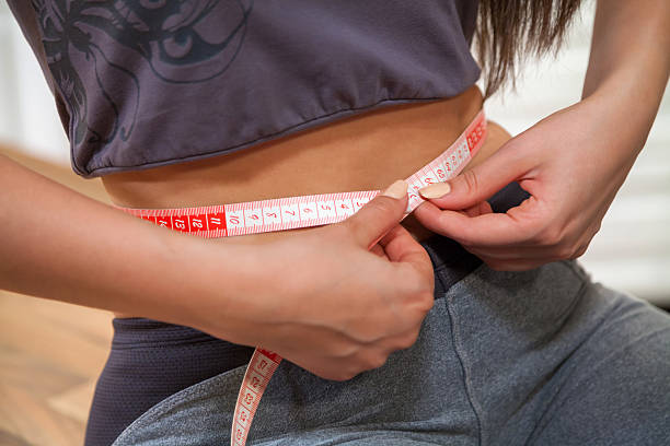 istock Holding tape measure around waist. 500265504
