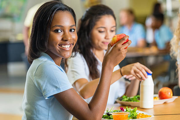 adolescente de comer saludable el almuerzo con amigos en la escuela comedor - apple healthy eating eating black fotografías e imágenes de stock