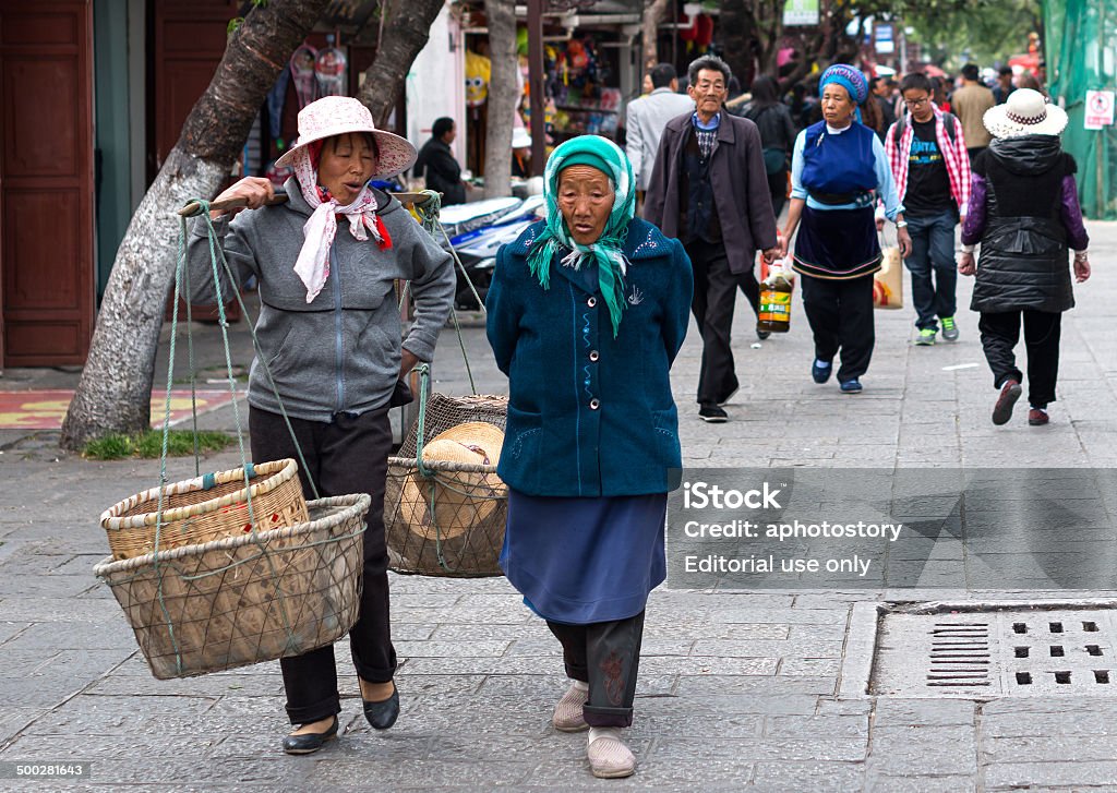 Farmers Dali, China - March 23, 2014: Farmers carrying pole walking in Fuxing road of Dali Ancient City, Yunnan Province, China. Ceremony Stock Photo