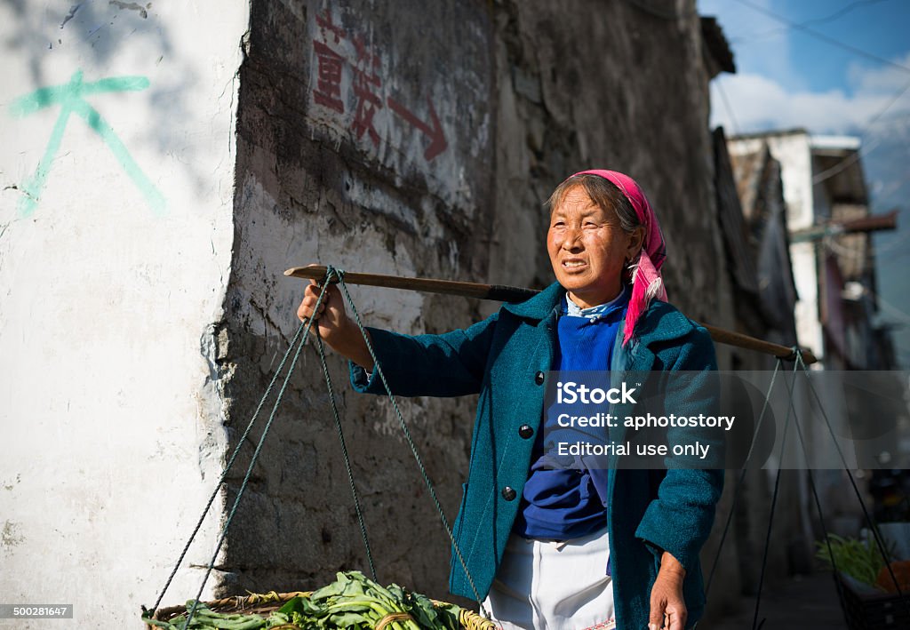 Farmers Dali, China - March 24, 2014: Farmers carrying pole walking in Dali Ancient City, Yunnan, China. Adult Stock Photo