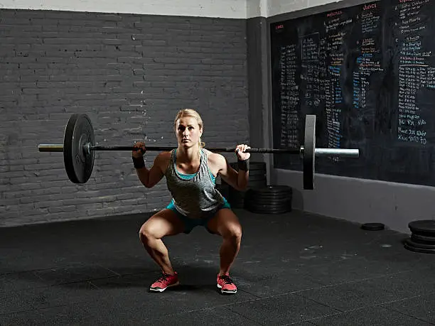 Female gym performing back squat in gym