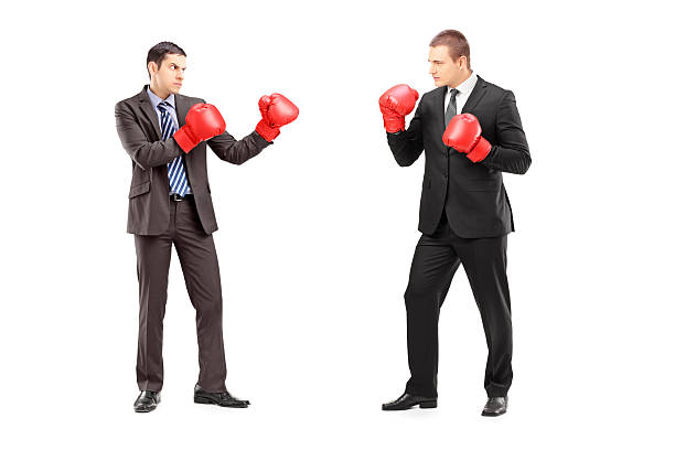 Two businessmen having a fight with boxing gloves Full length portrait of two businessmen having a fight with boxing gloves, isolated on white background violence boxing fighting combative sport stock pictures, royalty-free photos & images