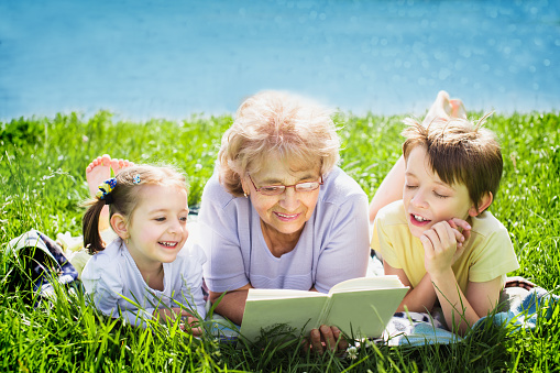 Grandmother reading a book for grandchildren, outdoors