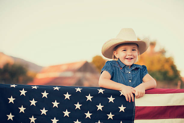 jeune cowgirl américaine avec drapeau américain - child flag fourth of july little girls photos et images de collection