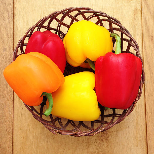 Red, yellow and orange bell peppers in basket. Raw vegetables.