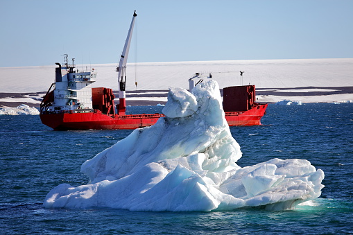 Iceberg and cargo ship in Arctic during summer naviagation