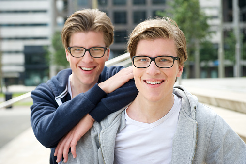 Close up portrait of two brothers with glasses smiling outdoors
