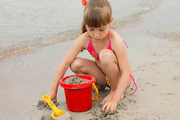 istock Girl playing with sand on the sea shore 500295715