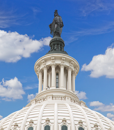 Close-up of Capitol Building Dome with Statue of Freedom, Washington DC. Vivid blue sky with clouds is in background