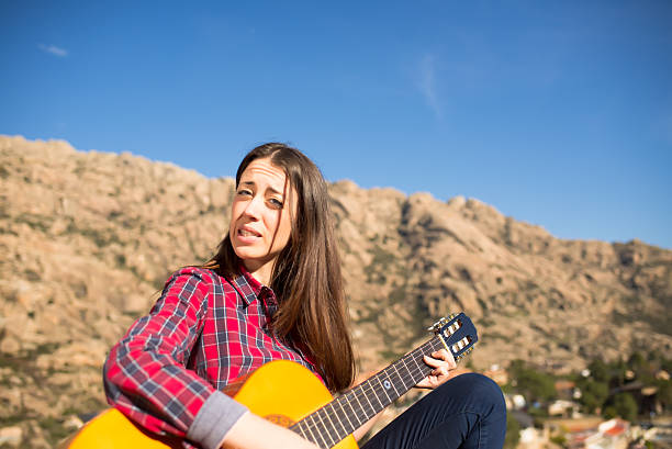 istock Cute Woman on a Rock while playing a Guitar 500300738