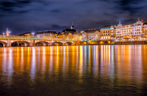 View over the river Rhine on the historic town of Basel, the decorated old stone bridge (Mittlere Brücke (Middle or Central Bridge)) illuminated with christmas lights.