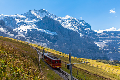 Train of Jungfraubahn running towards Jungfraujoch under the famous peak Jungfrau near the station Eigergletscher on bernese Oberland, Switzerland.