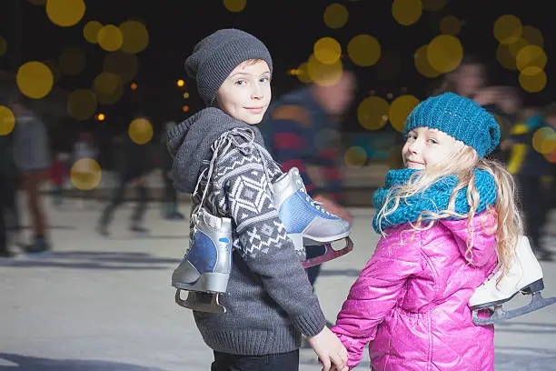 Photo of Happy children ice skating at ice rink, winter night