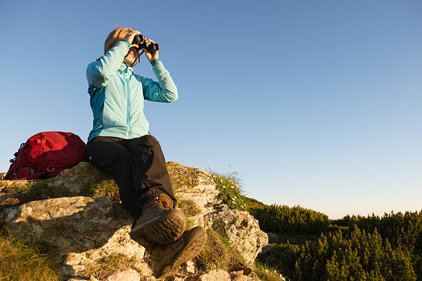 młoda kobieta gospodarstwa lornetki w odkryty ustawienie - mountain climbing pursuit women sunset zdjęcia i obrazy z banku zdjęć